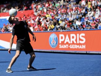 un jeune homme jonglant avec un ballon de foot, on peut voir le logo du PSG en fond